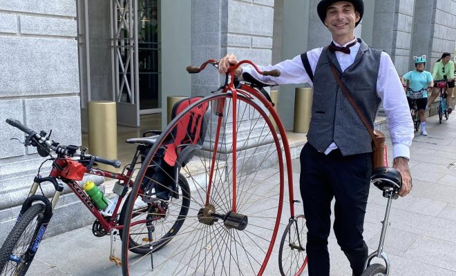 Man rides penny farthing during Car-Free Sunday 2024 in Spore, complete with top hat & suit
